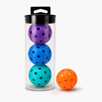 Clear tube of 4 pickleball balls in purple, blue and sky blue with an orange ball beside it