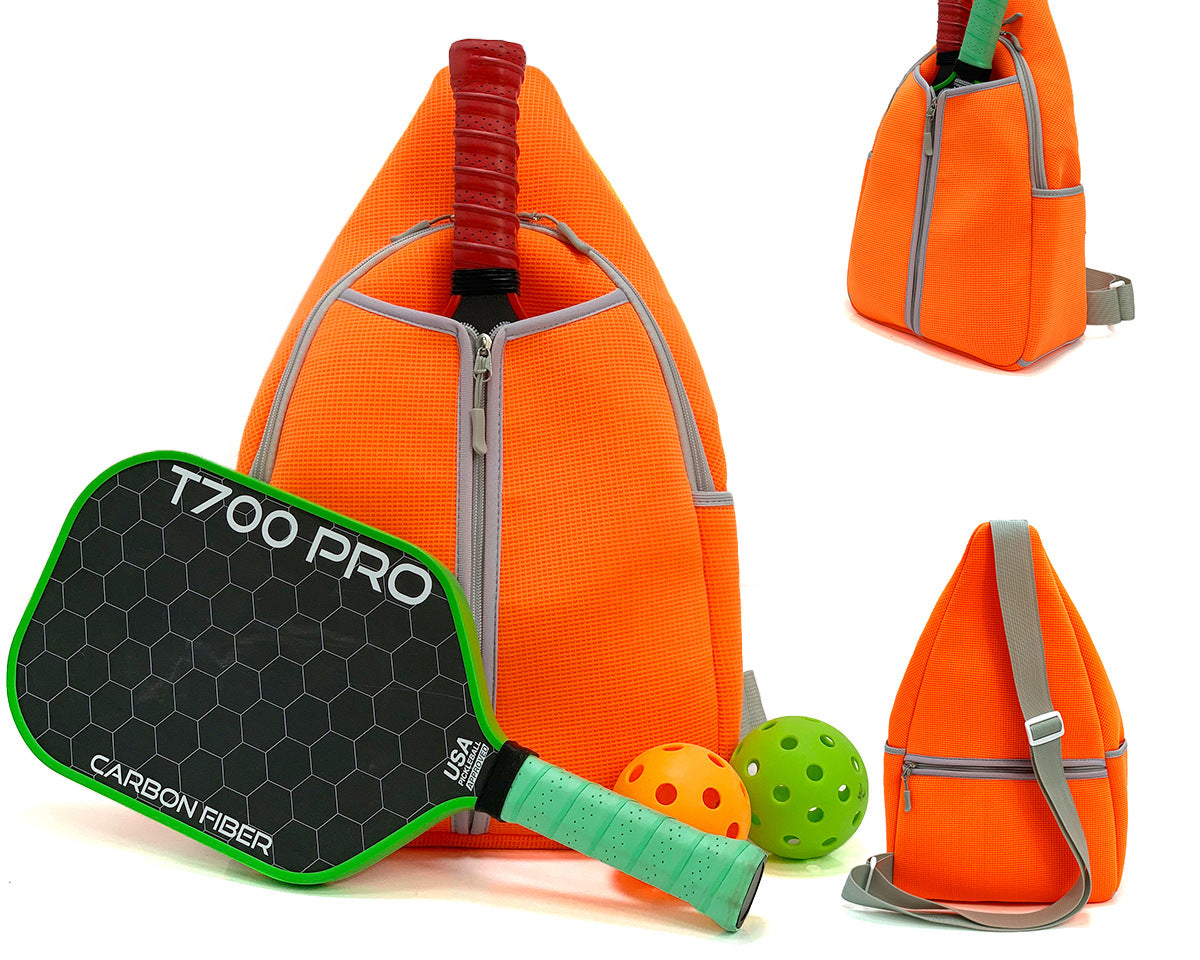 Orange neoprene pickleball sling bag with honeycomb texture front panel and adjustable crossbody strap shown with paddle and balls