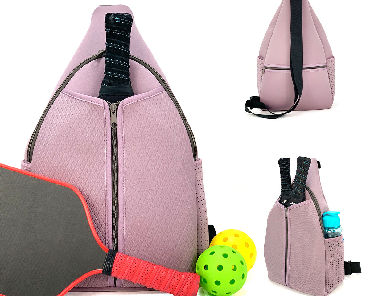 Purple neoprene pickleball sling bag with honeycomb texture front panel, front zipper pocket and adjustable crossbody strap shown with paddle and balls